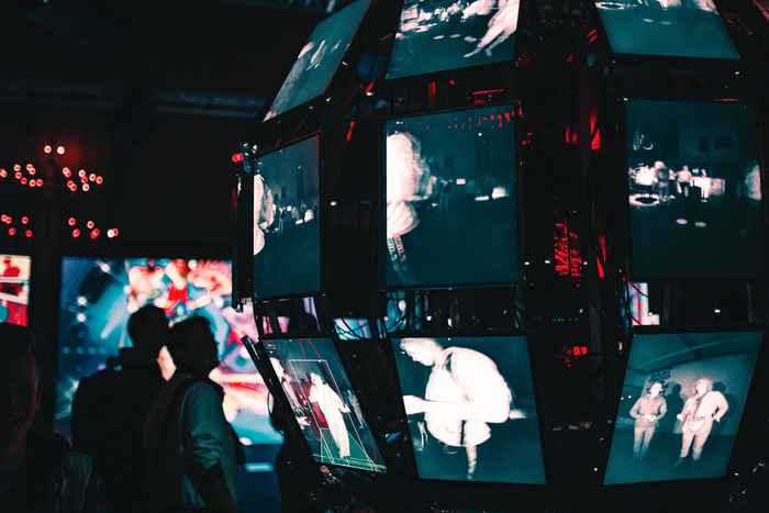 Mensen kijken op naar videoschermen die samen een grote bolvormige constellatie vormen