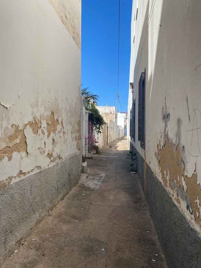 Beschadigde muren van huizen als gevolg van optrekkend vocht, een straat in Faro, Portugal.
