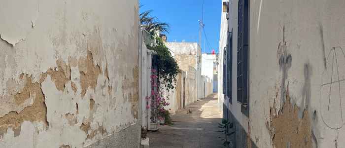 Beschadigde muren van huizen als gevolg van optrekkend vocht, een straat in Faro, Portugal.